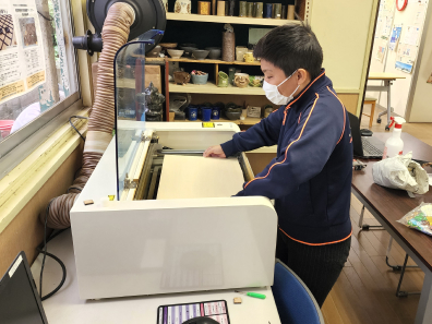 レーザー加工機にベニヤ板をセットしている写真