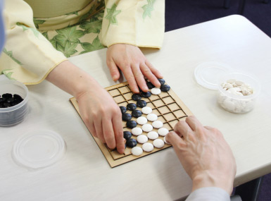 和服女性と柿島（アイゴツー9路盤で対局中の写真）