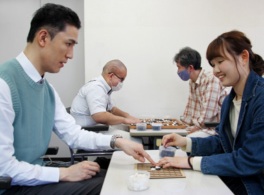 柿島（左）と女性（右）、アイゴツー9路盤で対局中の写真